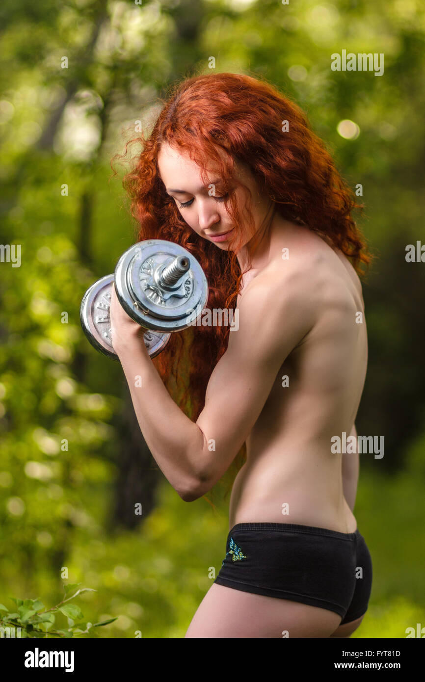 Redhead girl esercizio con manubri in foresta Foto Stock