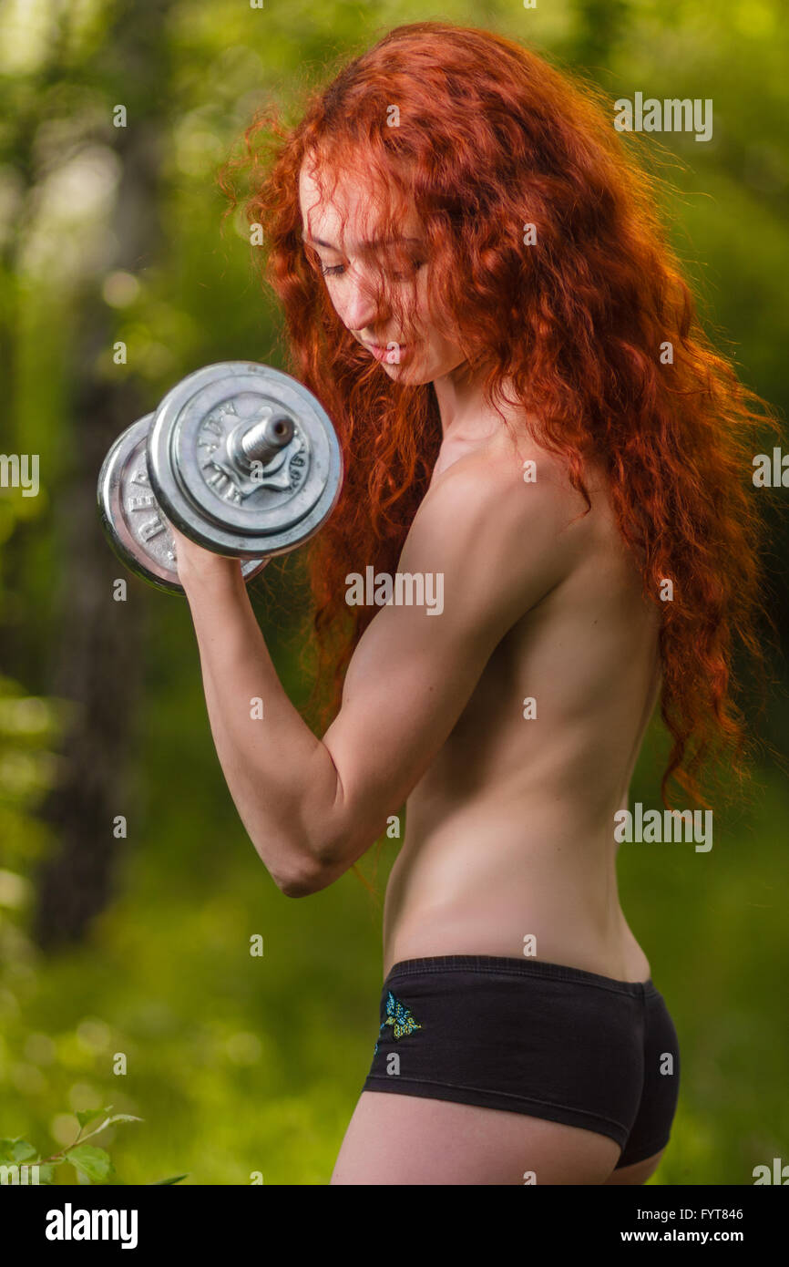 Redhead girl esercizio con manubri in foresta Foto Stock