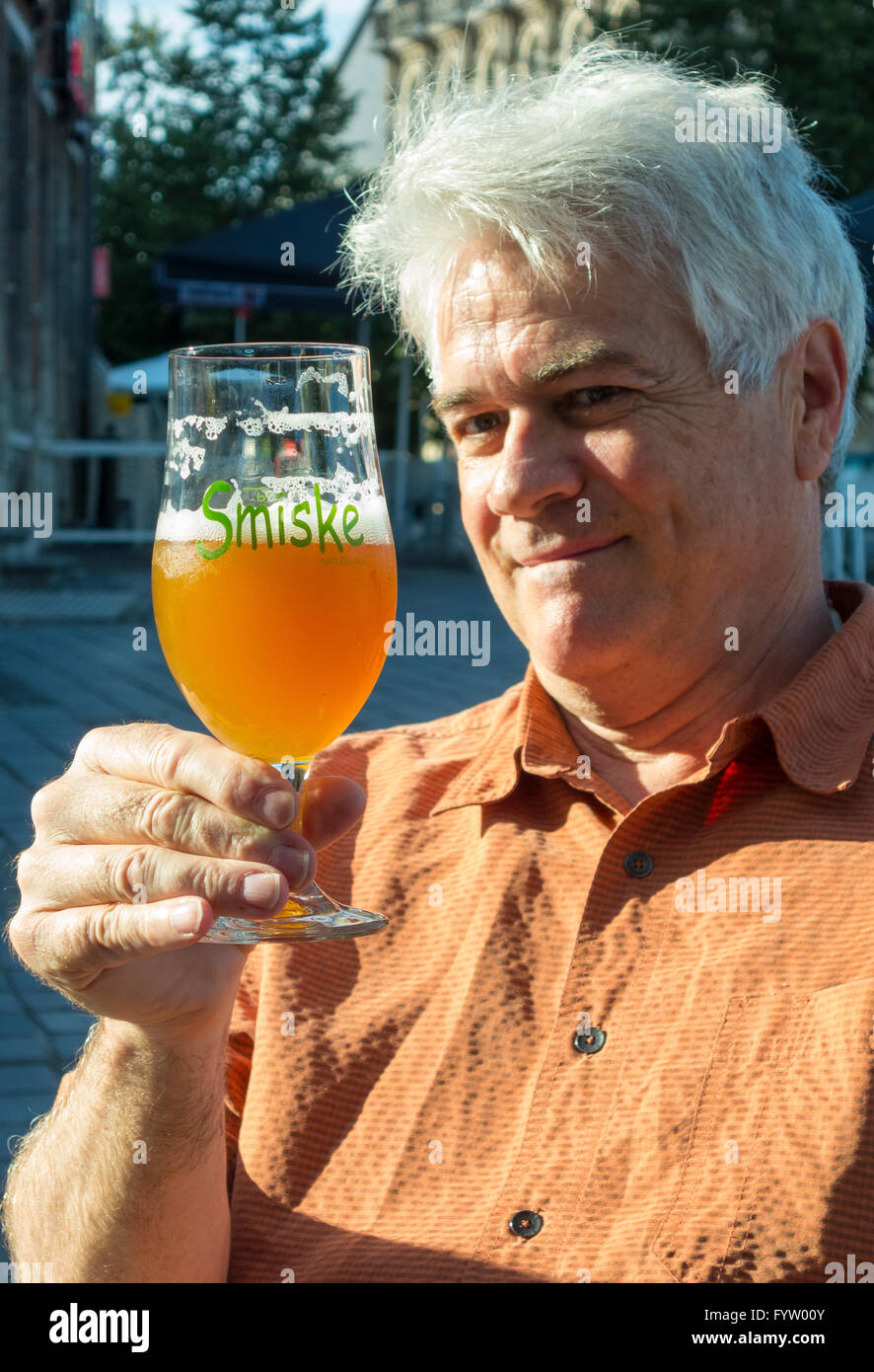 OUDENAARDE, Belgio - Uomo presso il cafe guarda al bicchiere di Smiske birra bionda, un belga microbrew. Foto Stock