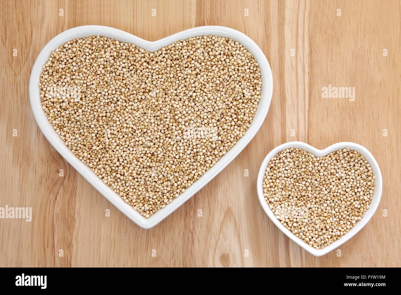 La quinoa grano super cibo nel cuore a forma di piatti di porcellana con legno di faggio sfondo. Foto Stock