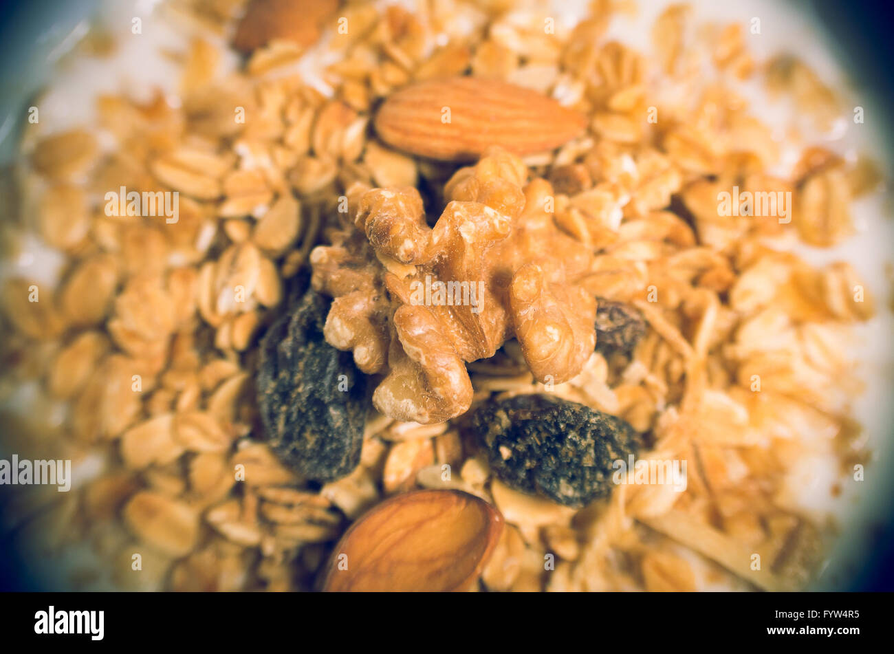 Vista dettagliata del sano mix di muesli con alcune mandorle e uvetta e latte di angolo di cui sopra Foto Stock