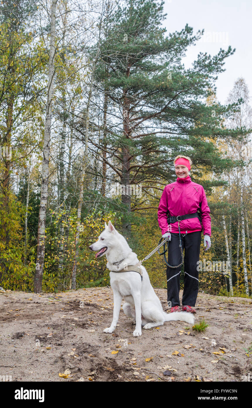 Donna con un cane bianco in un legno Foto Stock