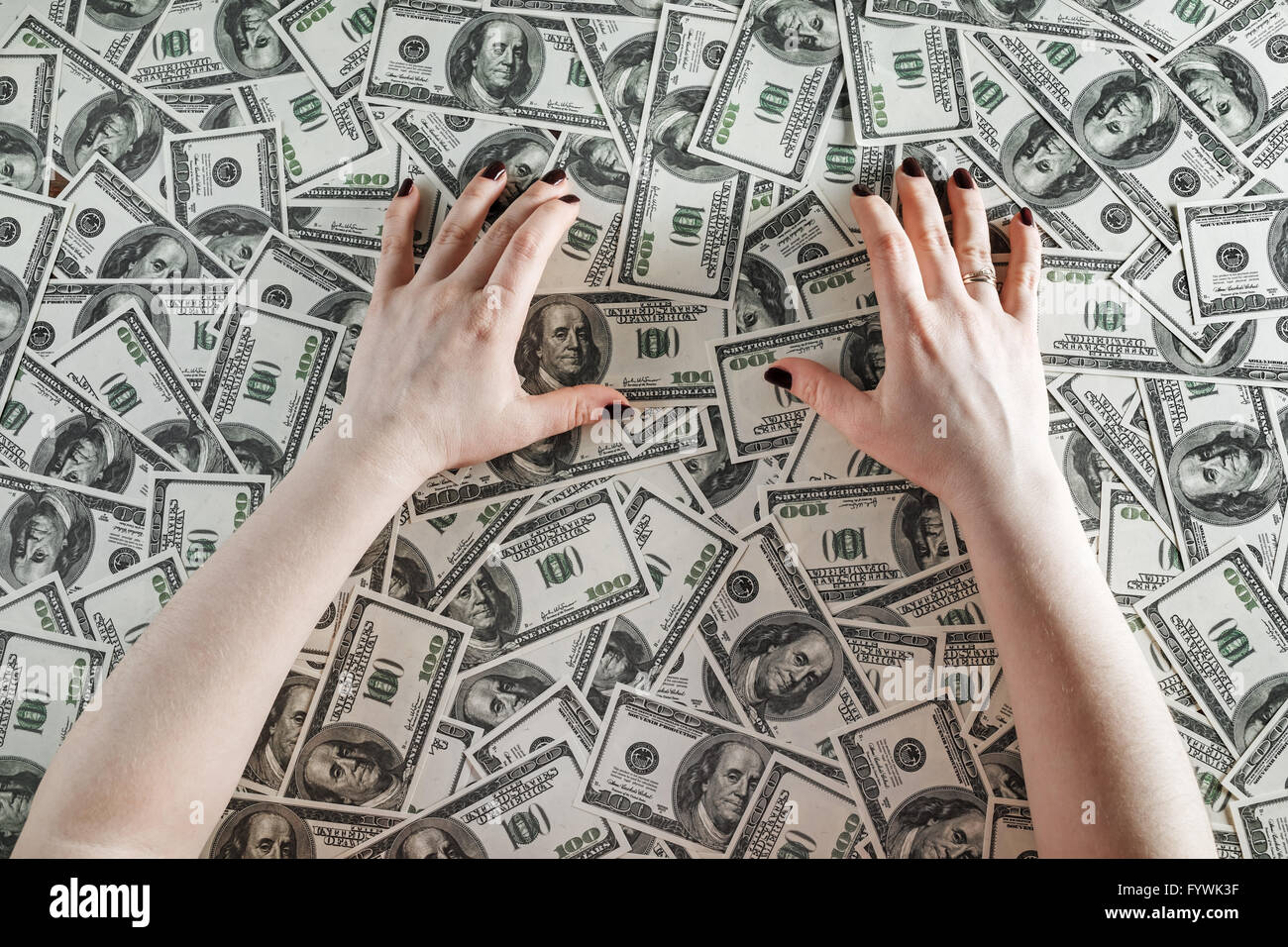 Mani femminili su uno sfondo di denaro. Mani e denaro. Molte banconote da cento dollari. Denaro falso. Il concetto di business. Vista dall'alto. Foto Stock