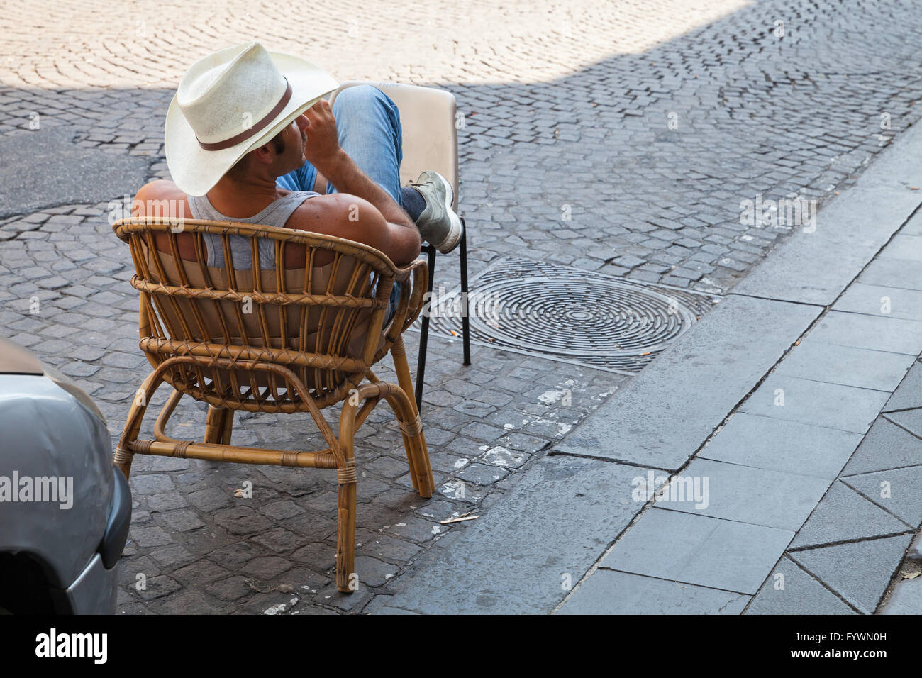 Napoli, Italia - Agosto 9, 2015: parcheggio illegale servizio, forte uomo seduto sul ciglio della strada per auto prenotazione del posto Foto Stock