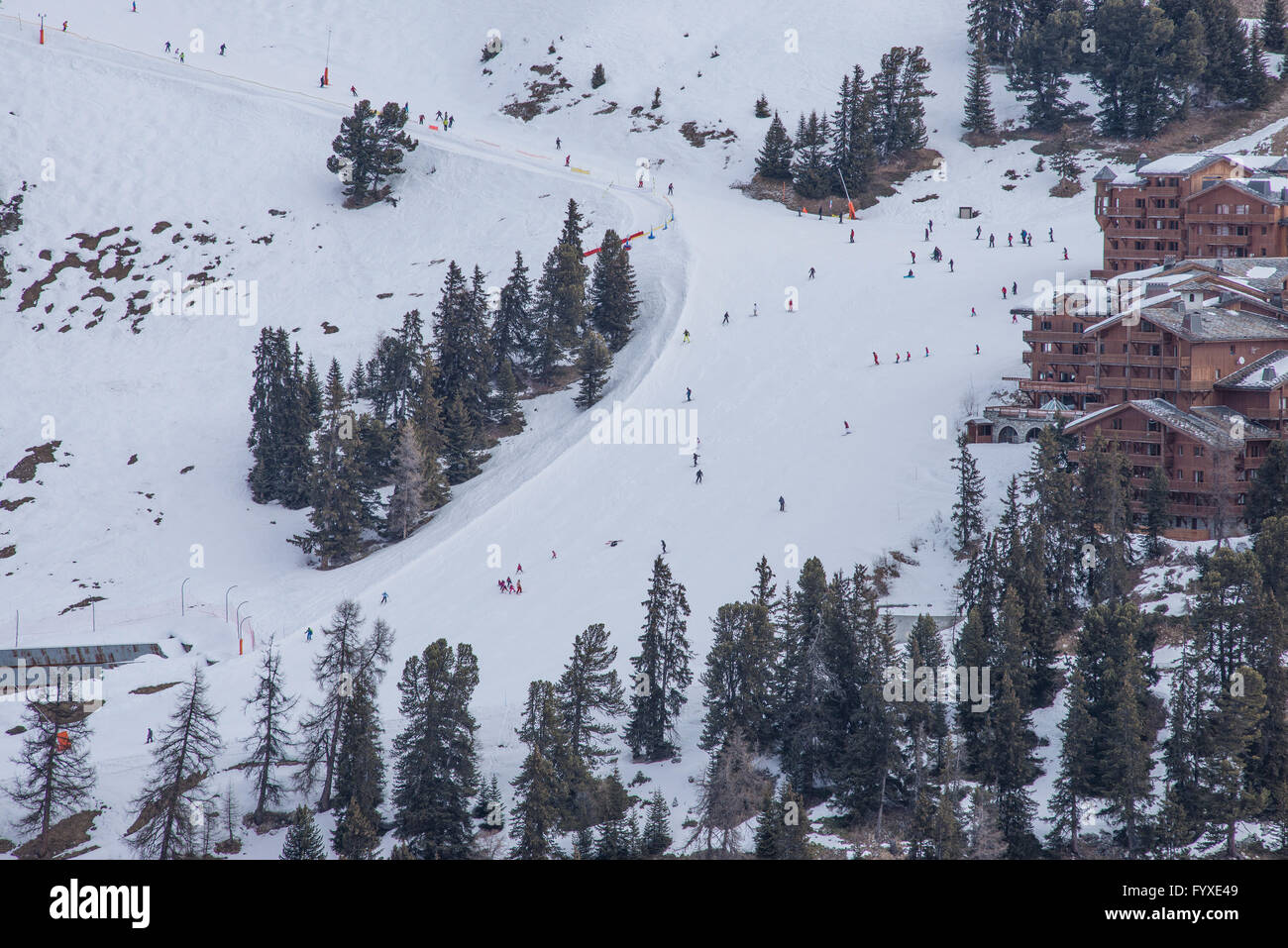 Gli sciatori su ampia pista blu passando il francese alpine ski resort villaggio di Belle Plagne in Tarentaise. Foto Stock