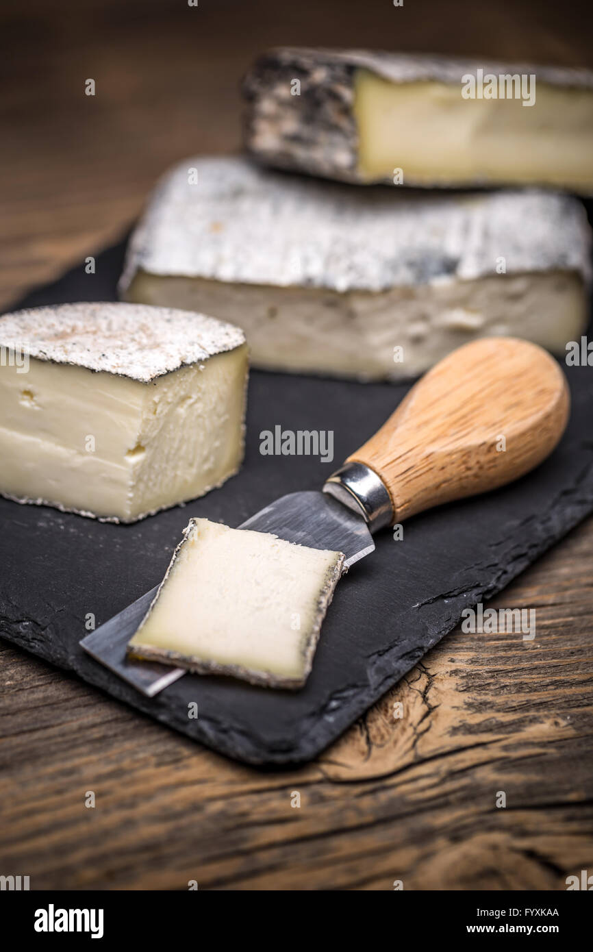 Formaggio a pasta morbida pezzi su nero ardesia Foto Stock