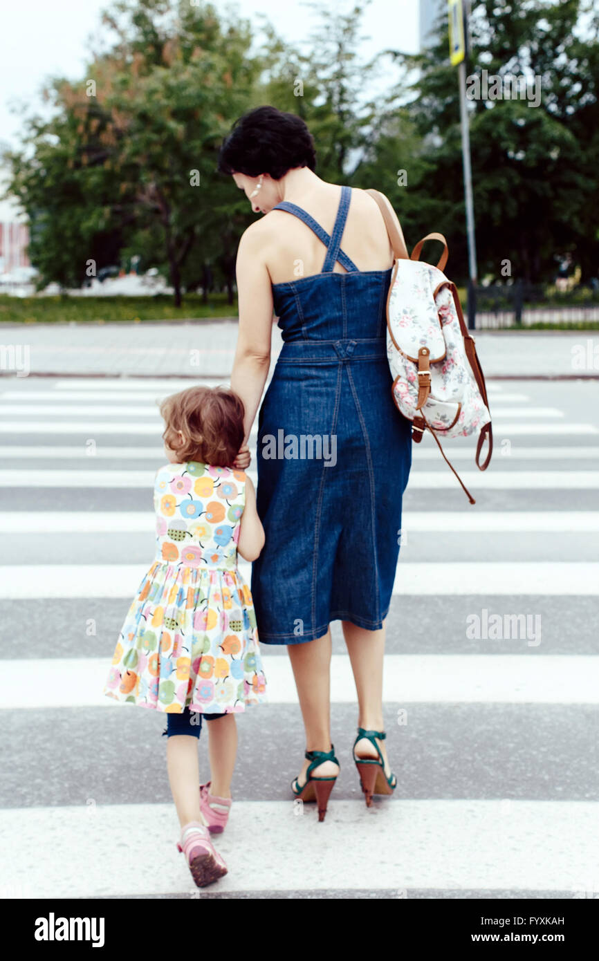 Figlia con sua madre attraversando la strada Foto Stock