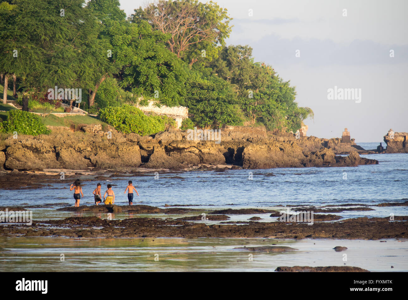 Bambini che giocano sulle rocce al lato sud della baia di Jimbaran, Bali. Foto Stock