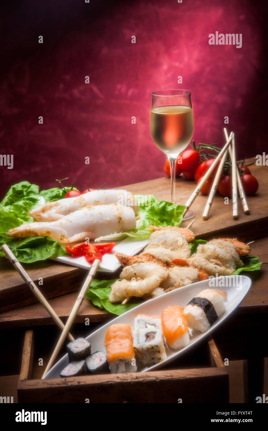 Insalata di mare con zucchine e pomodori con un bicchiere di vino bianco e calamari ripieni Foto Stock
