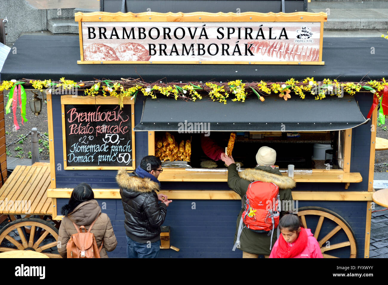 Praga, Repubblica Ceca. Mercato di pasqua nella Piazza della Città Vecchia, 2016. Persone mangiare 'Bramborova Spirala' - spirali di patata... Foto Stock