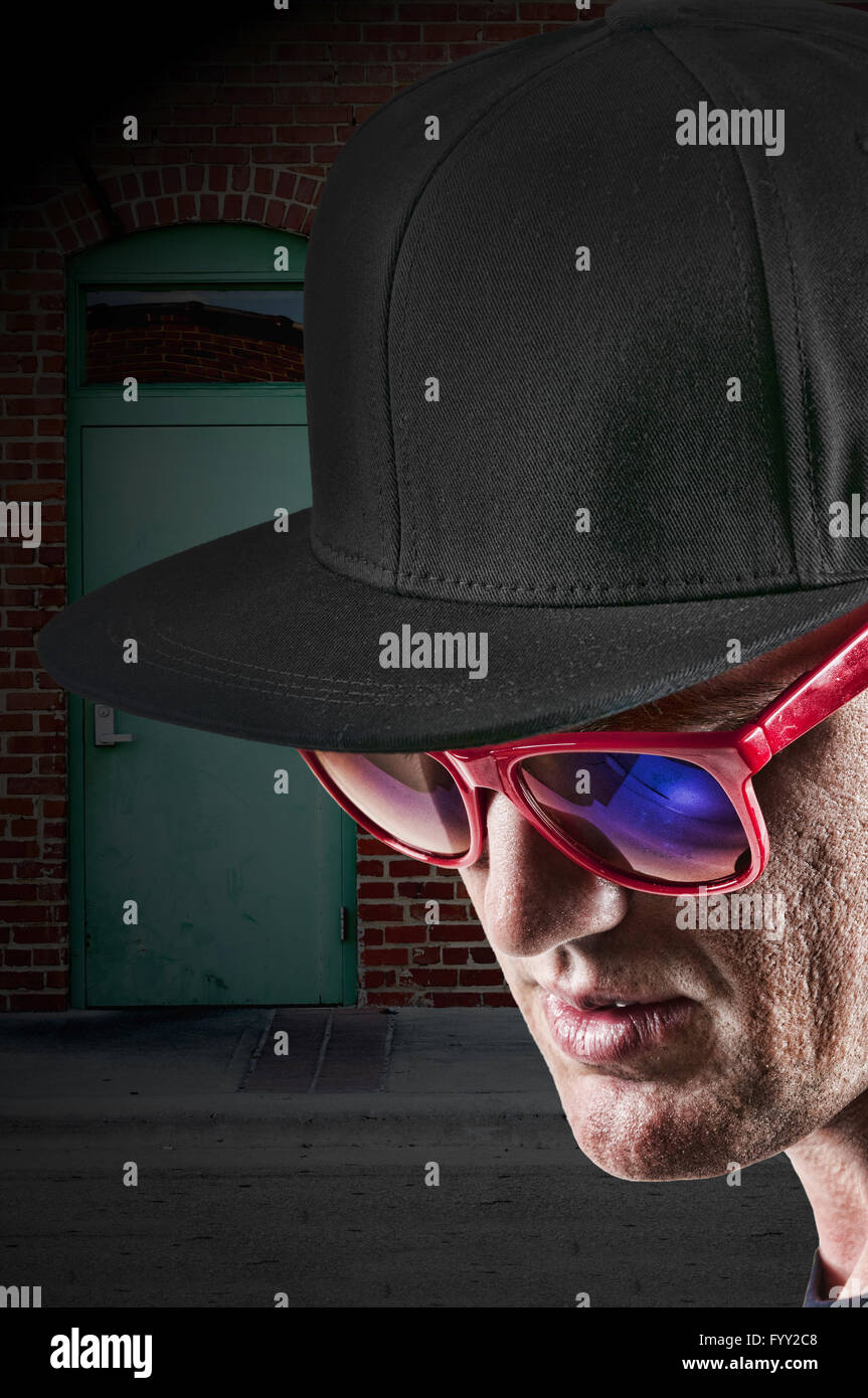Uomo che indossa cappello da baseball e occhiali da sole Foto Stock