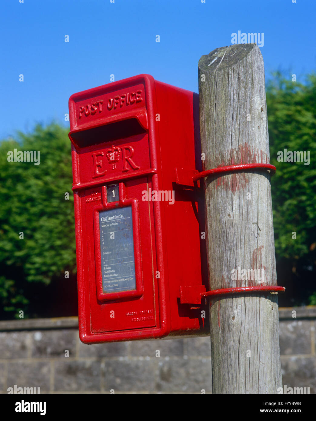 Postbox rosso su un bastone di legno, all'esterno. Foto Stock