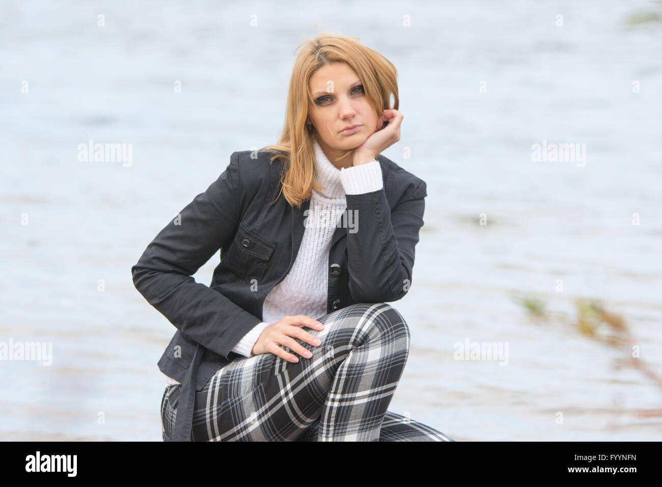 Bella ragazza triste sat dal fiume nel caldo clima autunnale Foto Stock