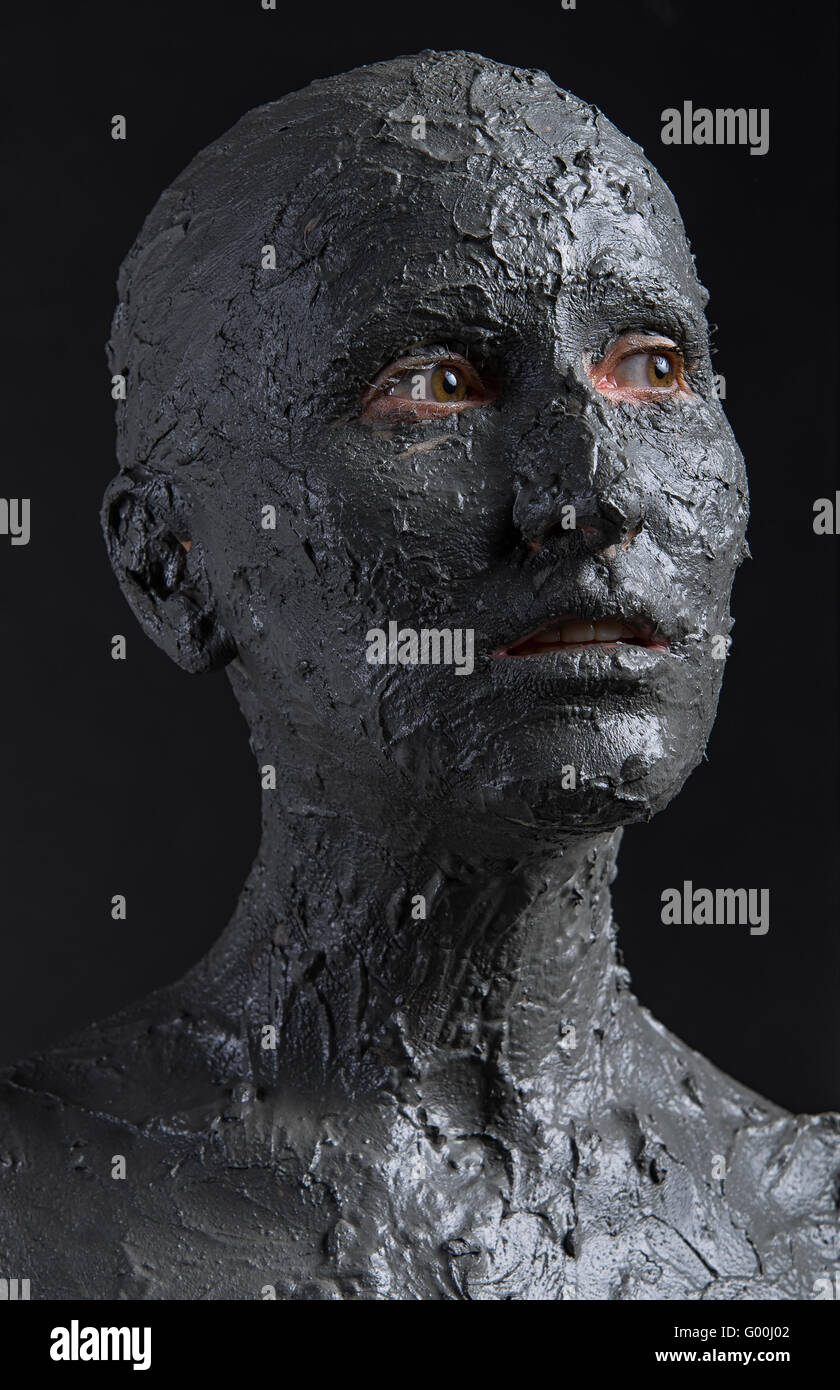 Statuario donna in argilla bagnata. La donna coperta in argilla bagnata. Il trattamento termale o Scary Halloween mask? Foto Stock