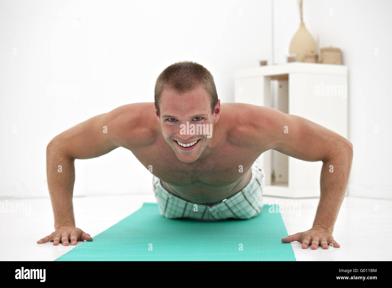 Giovane uomo che fa pushups su un tappeto verde Foto Stock