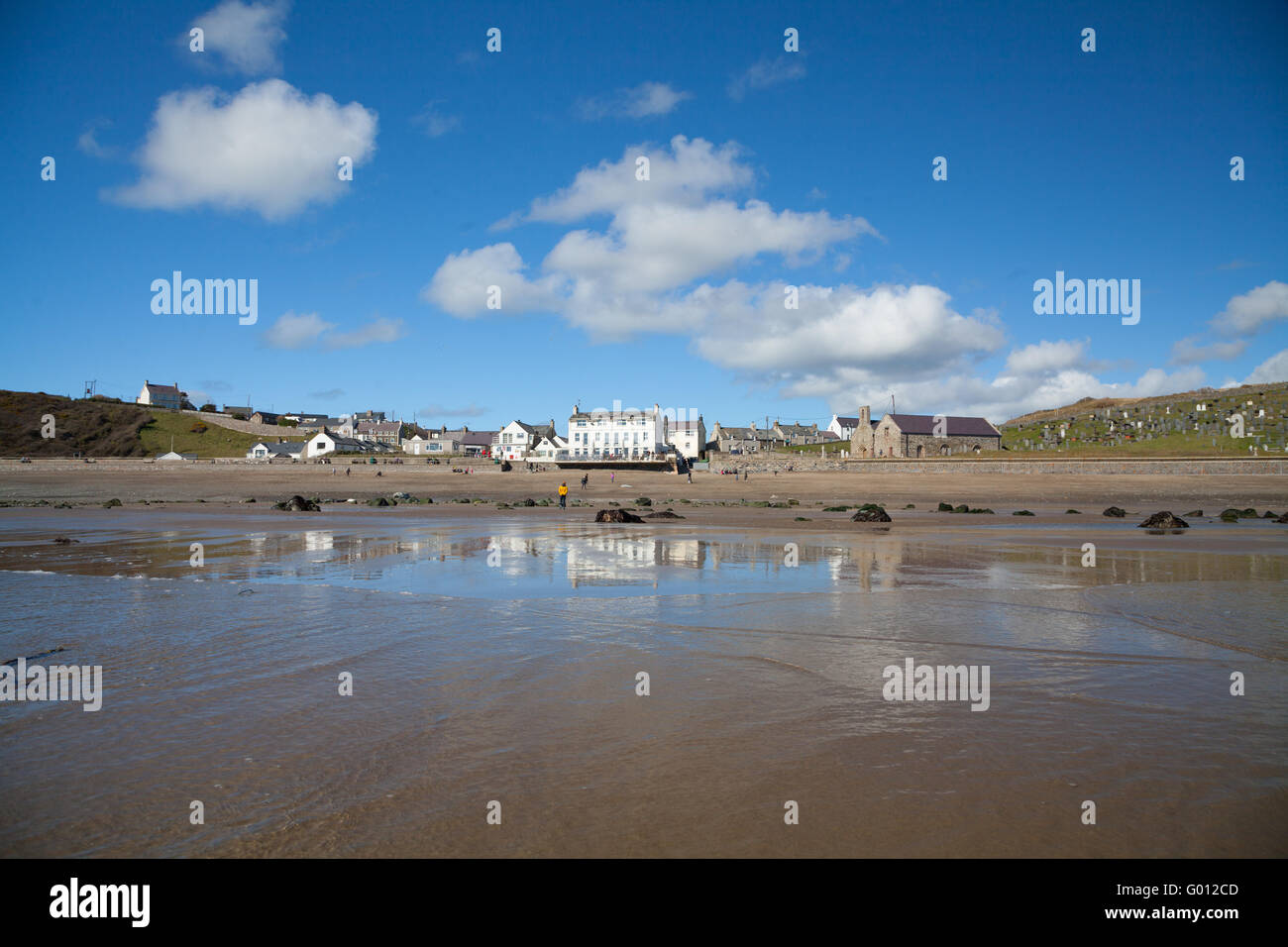 La vista verso Aberdaron village (mostra pub & chiesa) presi dalla spiaggia con la bassa marea su un estate giornata di primavera con il blu del cielo Foto Stock