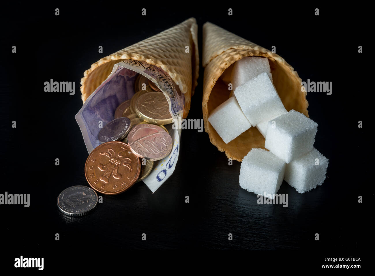 Coni con cubetti di zucchero in uno e denaro (pound note e pence monete) simboleggia la tassa di zucchero nel Regno Unito Foto Stock
