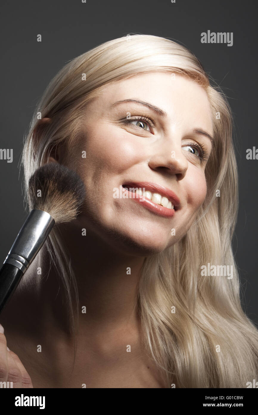 Ritratto di sorridente giovane donna con il trucco pennello Foto Stock