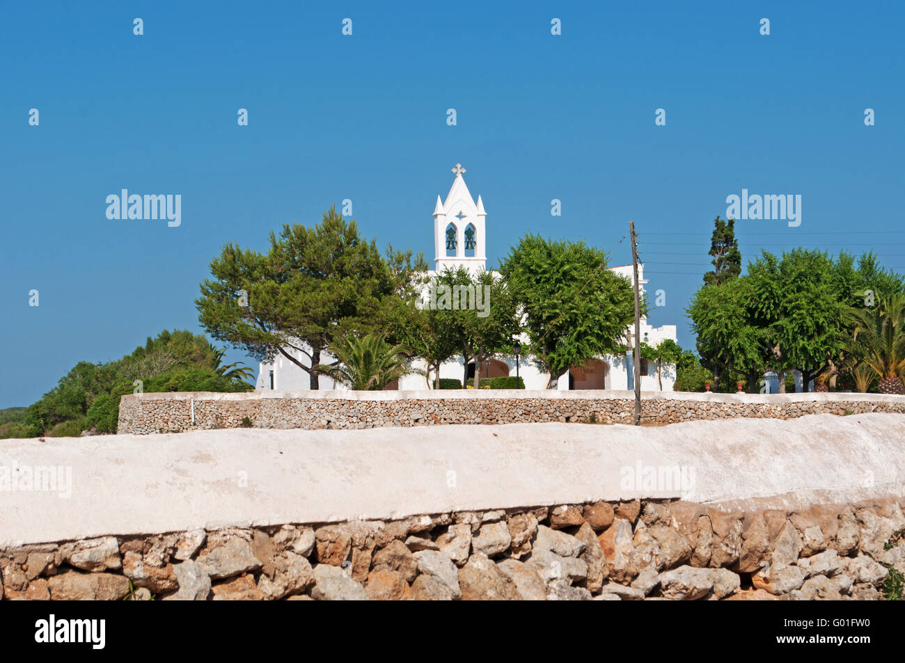 Minorca isole Baleari, Spagna, Europa: un muro di pietra e una chiesa bianca nella campagna menorcan Foto Stock