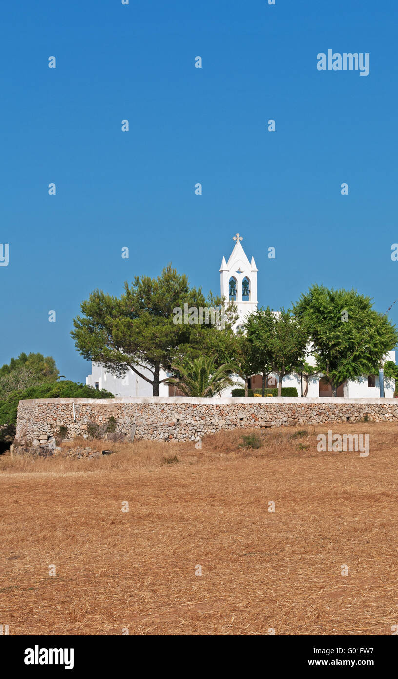 Minorca isole Baleari, Spagna, Europa: un muro di pietra e una chiesa bianca nella campagna menorcan Foto Stock