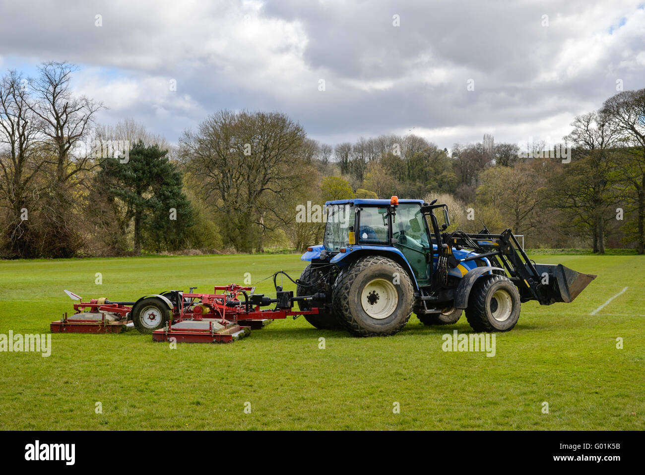 Il trattore falciare l'erba su un campo di calcio in un parco pubblico in Inghilterra. Foto Stock