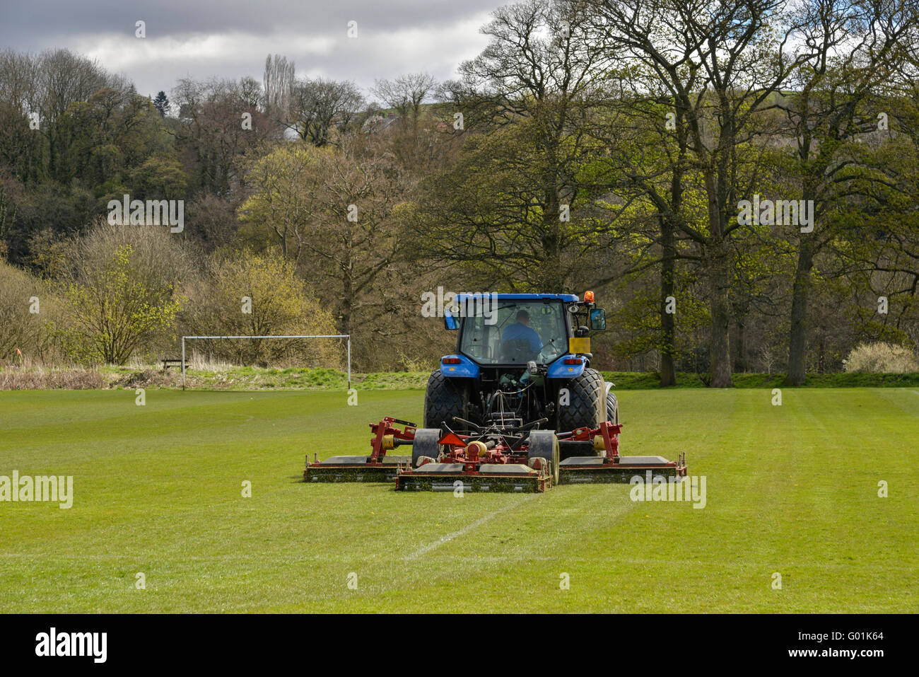 Il trattore falciare l'erba su un campo di calcio in un parco pubblico in Inghilterra. Foto Stock