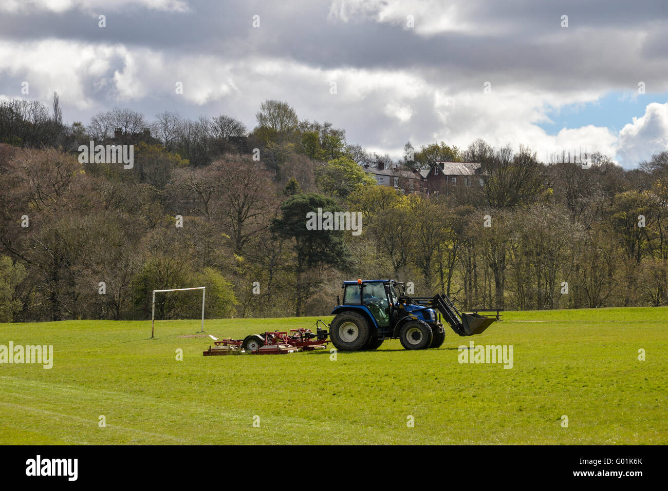 Il trattore falciare l'erba su un campo di calcio in un parco pubblico in Inghilterra. Foto Stock