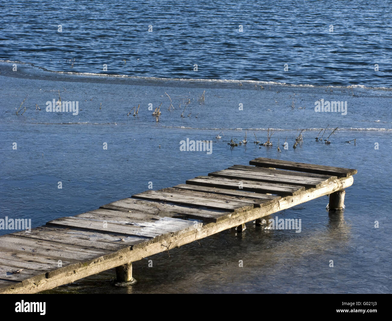 Congelato stagno con legno planked piedi modo sulla soleggiata giornata invernale Foto Stock
