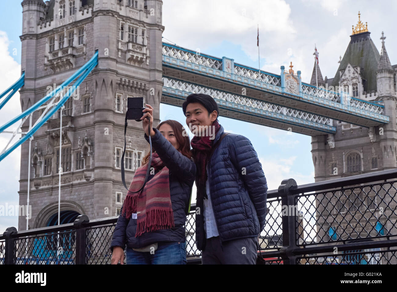 Turisti asiatici tenendo selfie con il Tower Bridge in background, Londra England Regno Unito Regno Unito Foto Stock