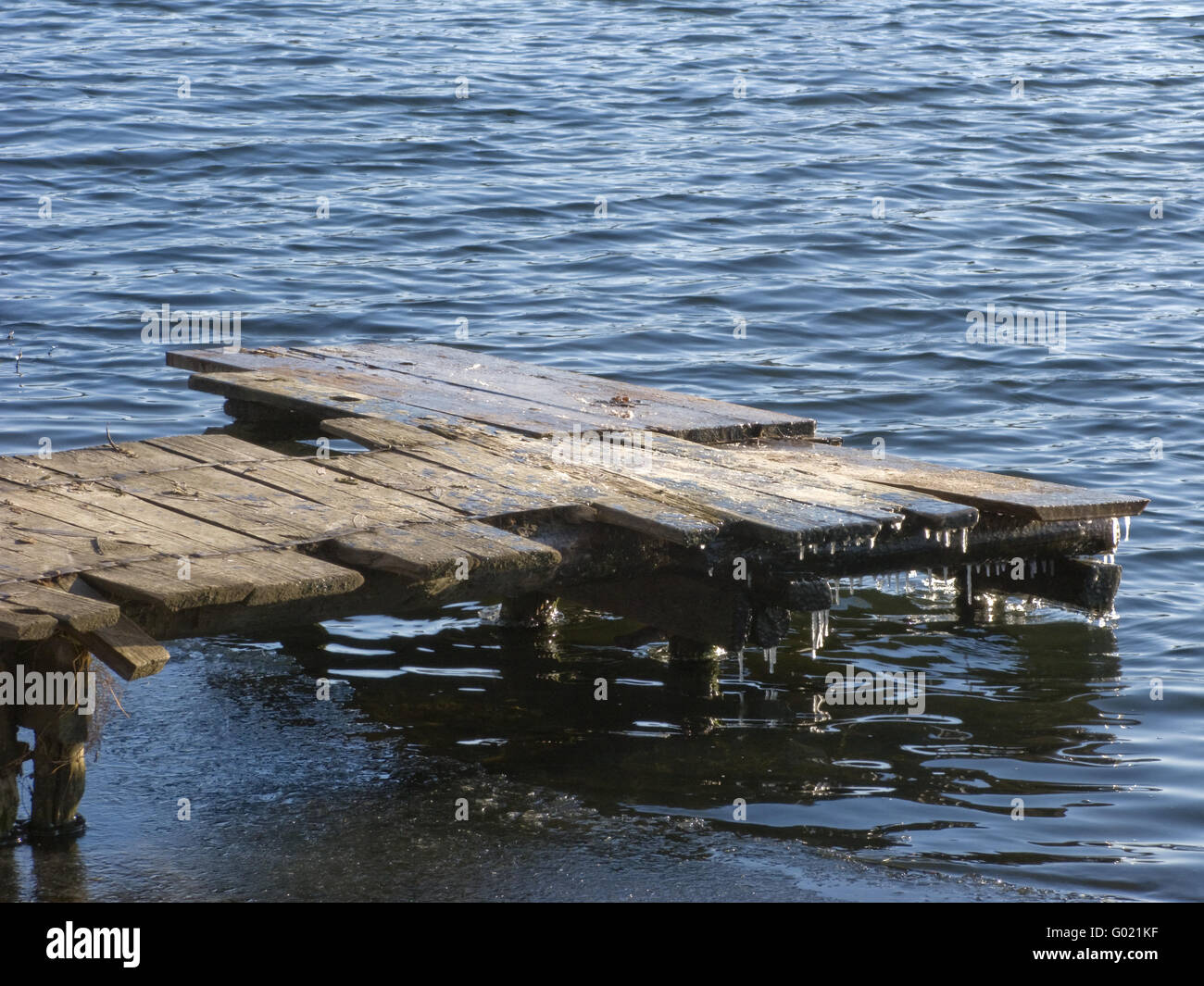 Congelato stagno con il vecchio legno piede planked modo sulla soleggiata giornata invernale Foto Stock