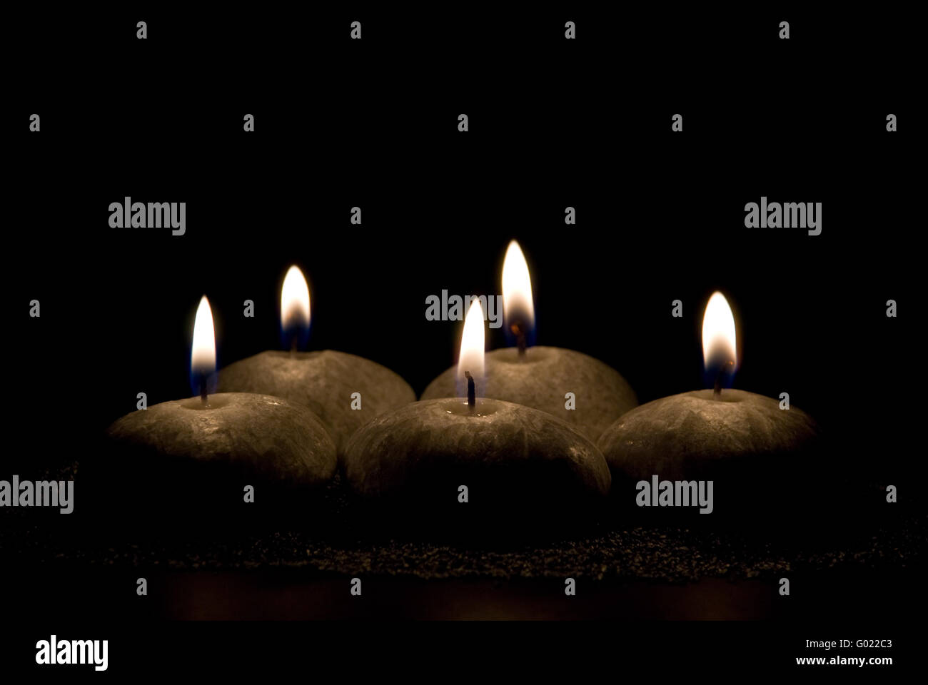 Cinque candele in forma di pietre su sfondo nero Foto Stock