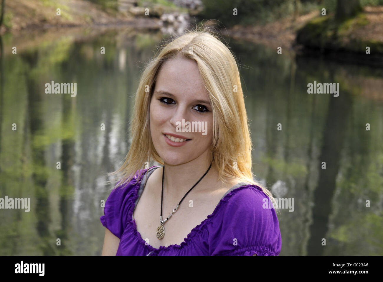 Giovane bionda ragazza in uno stagno in primavera. Casino park in Georgsmarienhuette, Bassa Sassonia, Germania Foto Stock