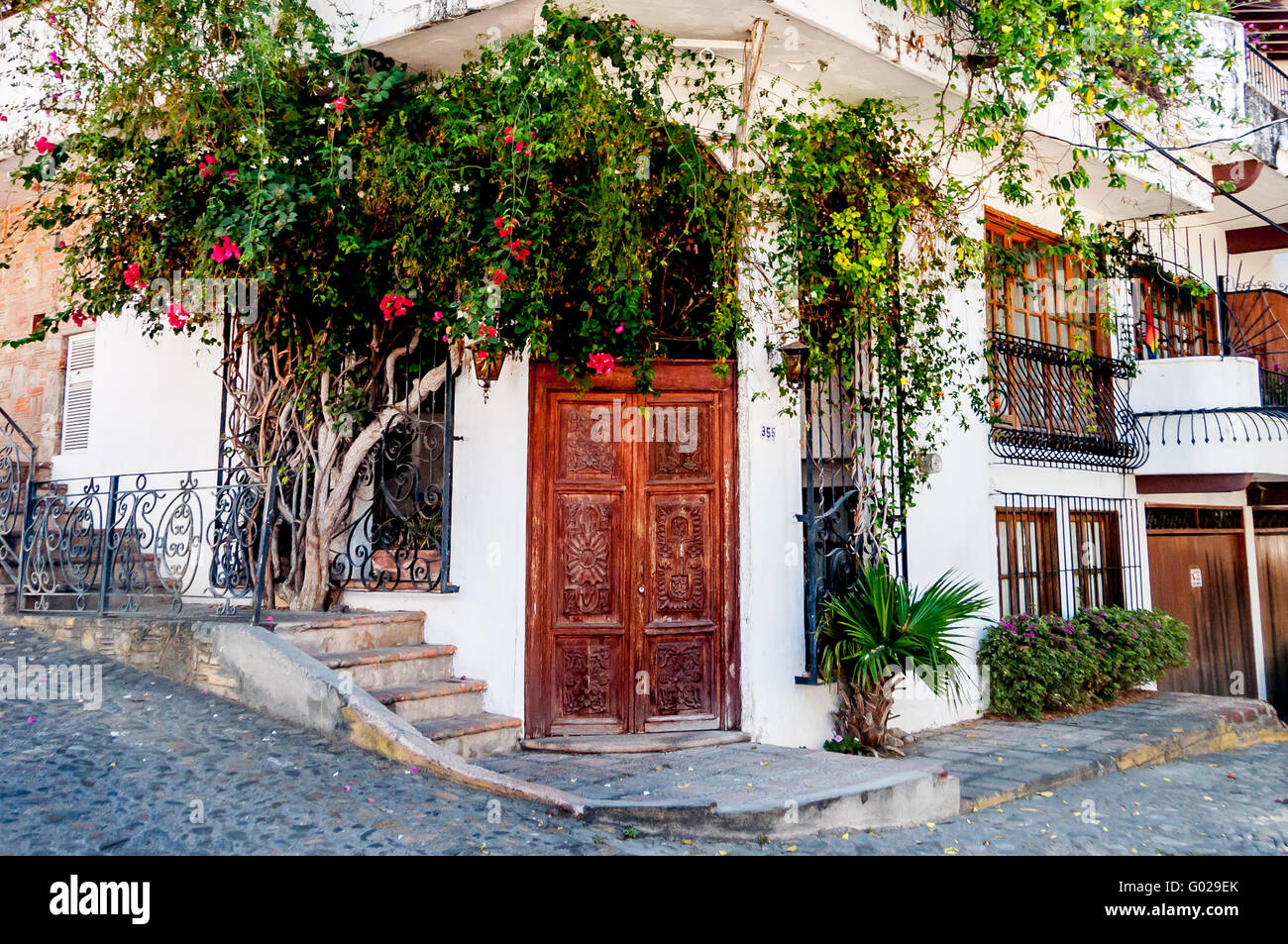 Porte di legno intagliato in Puerto Vallarta la Zona Romantica, con bouganville, letti in ferro battuto con aggiunta di romanticismo per l'edificio bianco Foto Stock