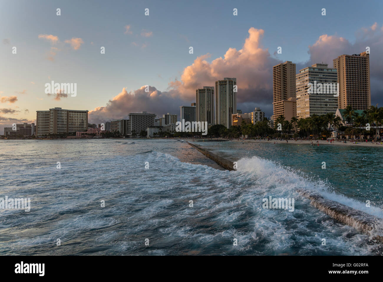 Kuhio Beach Park in Waikiki al tramonto con una vista dell'hotel. Foto Stock