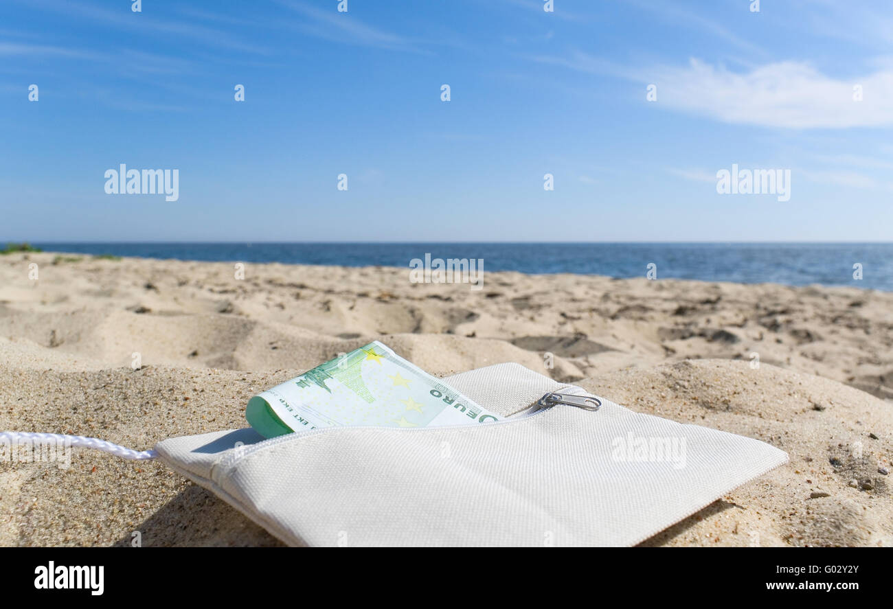 Borsa bianca con denaro sulla spiaggia. Foto Stock