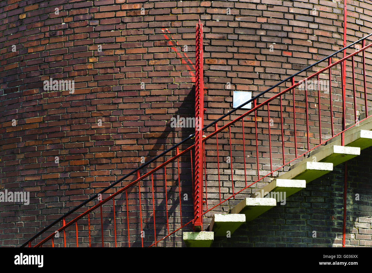 Scala di colore rosso a un muro di mattoni Foto Stock