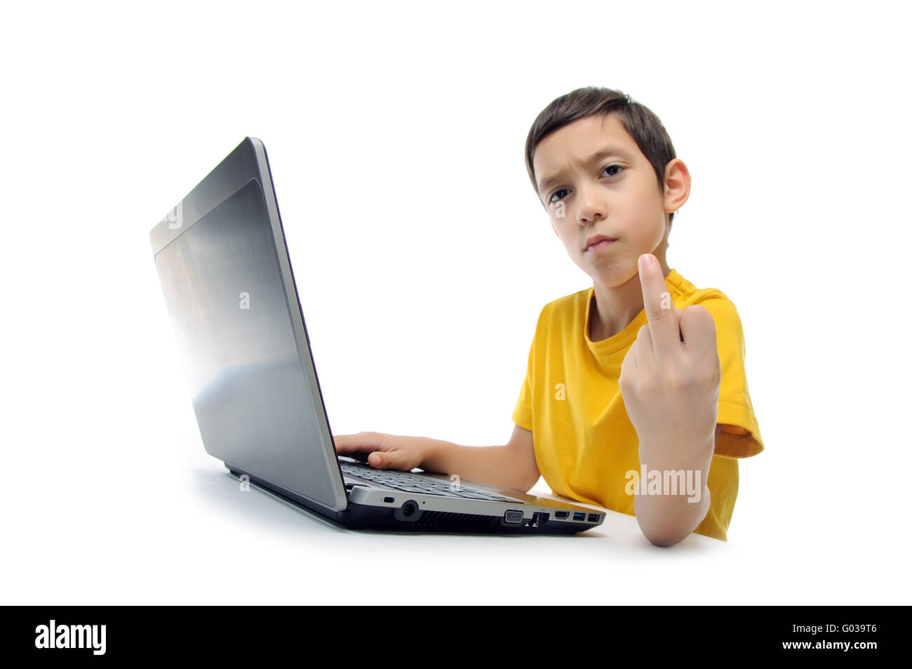 Arrabbiato ragazzo aggressivo in giallo t-shirt con il computer portatile che mostra il dito medio in telecamera isolata su sfondo bianco Foto Stock