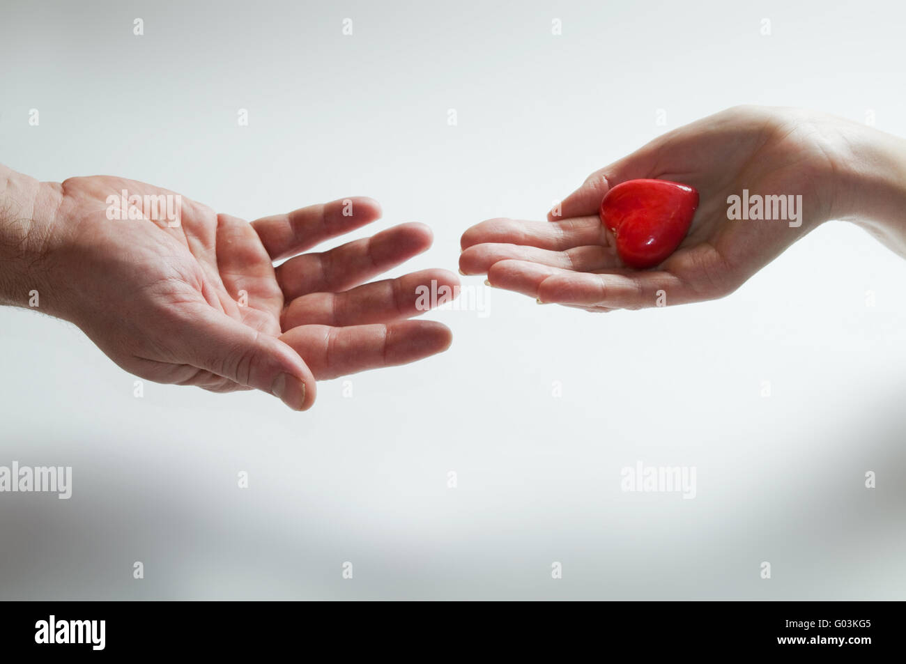 Dando cuore amore concetto. Una mano dà cuore simbolico ad un altro. Foto Stock