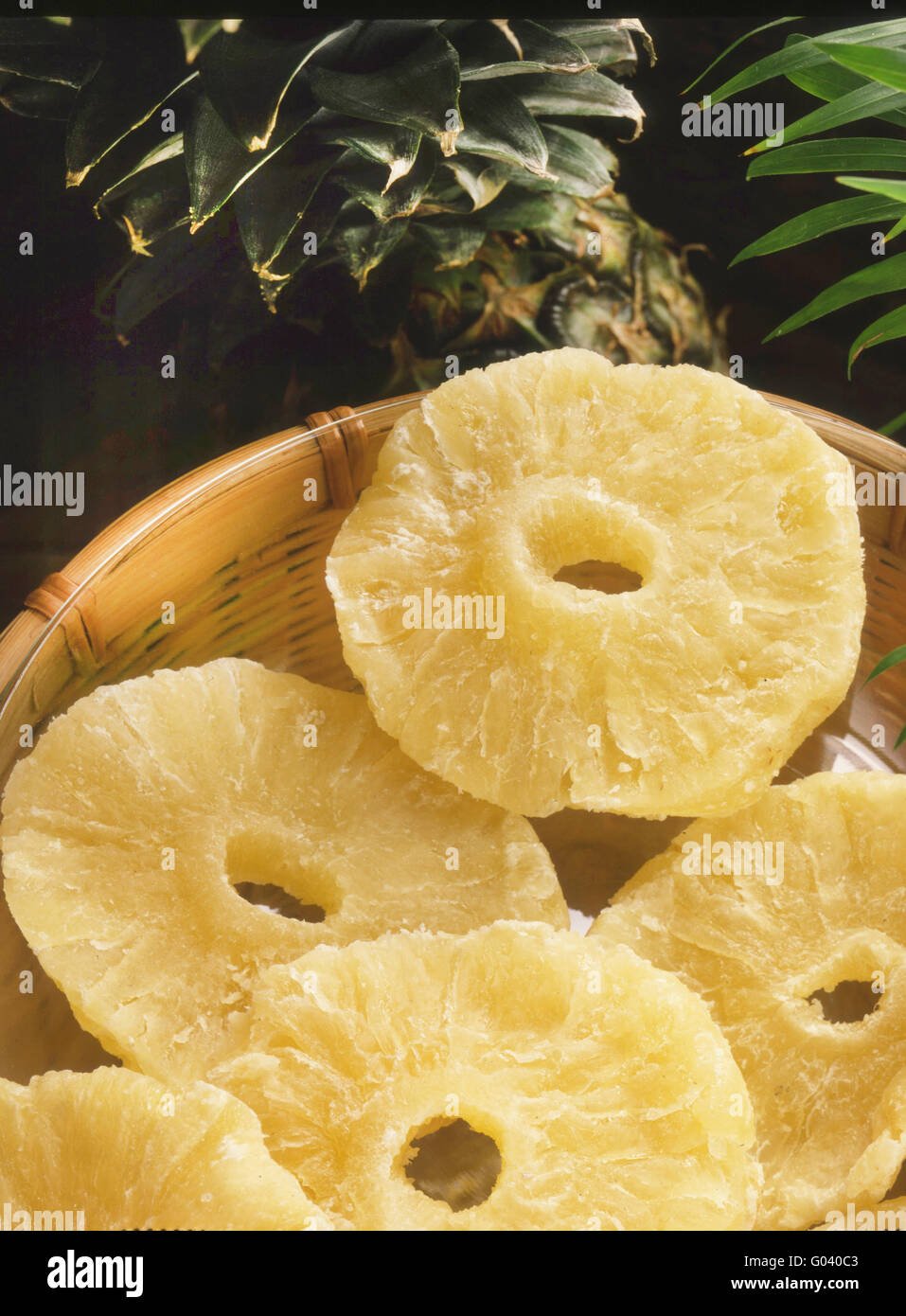 Essiccato anelli di ananas a fette in un vassoio di bambù con ananas fresco in background. Foto Stock
