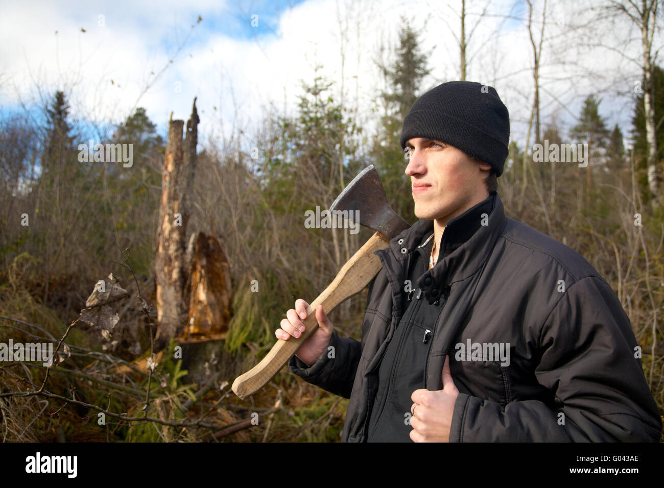 L'uomo con un'ascia guarda il tumbled giù il legno Foto Stock