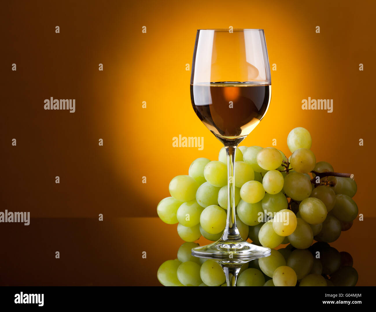 Un bicchiere di vino bianco e un grappolo di uva verde Foto Stock