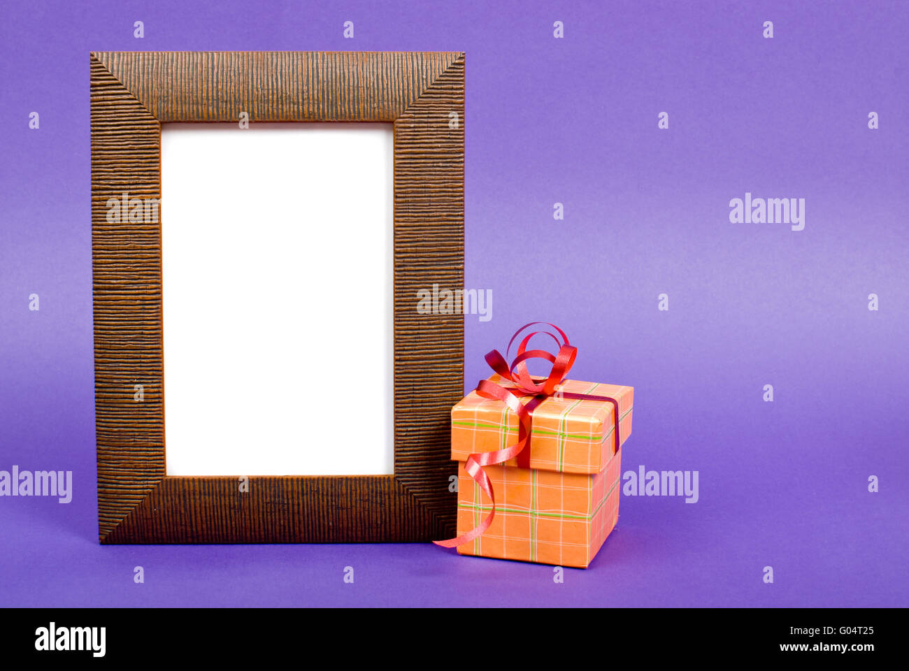 In legno cornice fotografica e orange box regalo con nastro rosso su sfondo blu. Foto Stock