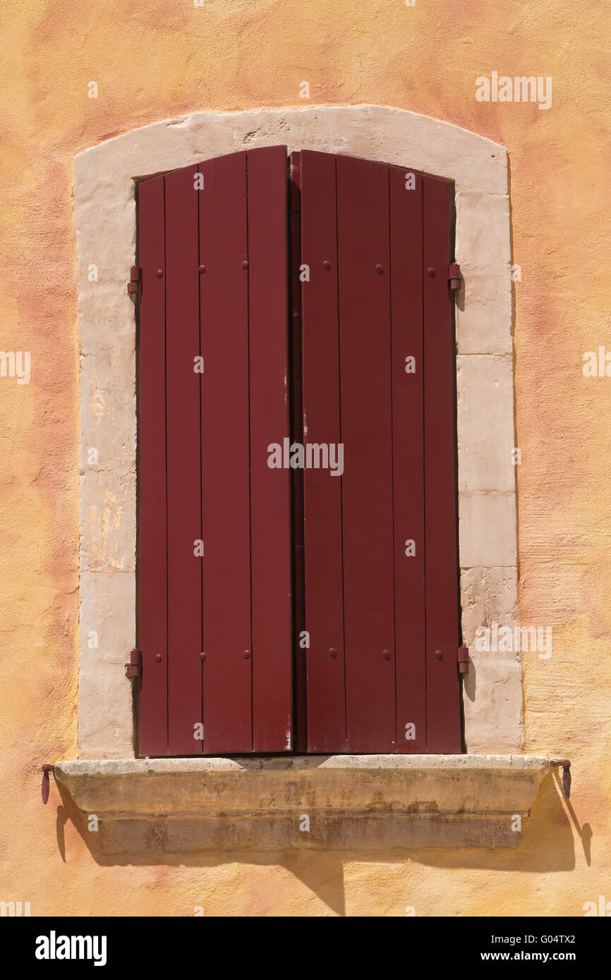 Vista ravvicinata della vecchia finestra con red persiane di legno. Architettura mediterranea. Provenza, Francia. Foto Stock