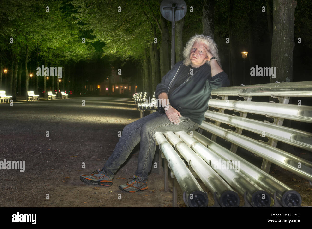 Un uomo si siede su una panchina nel giardino del cortile paglierino Foto Stock