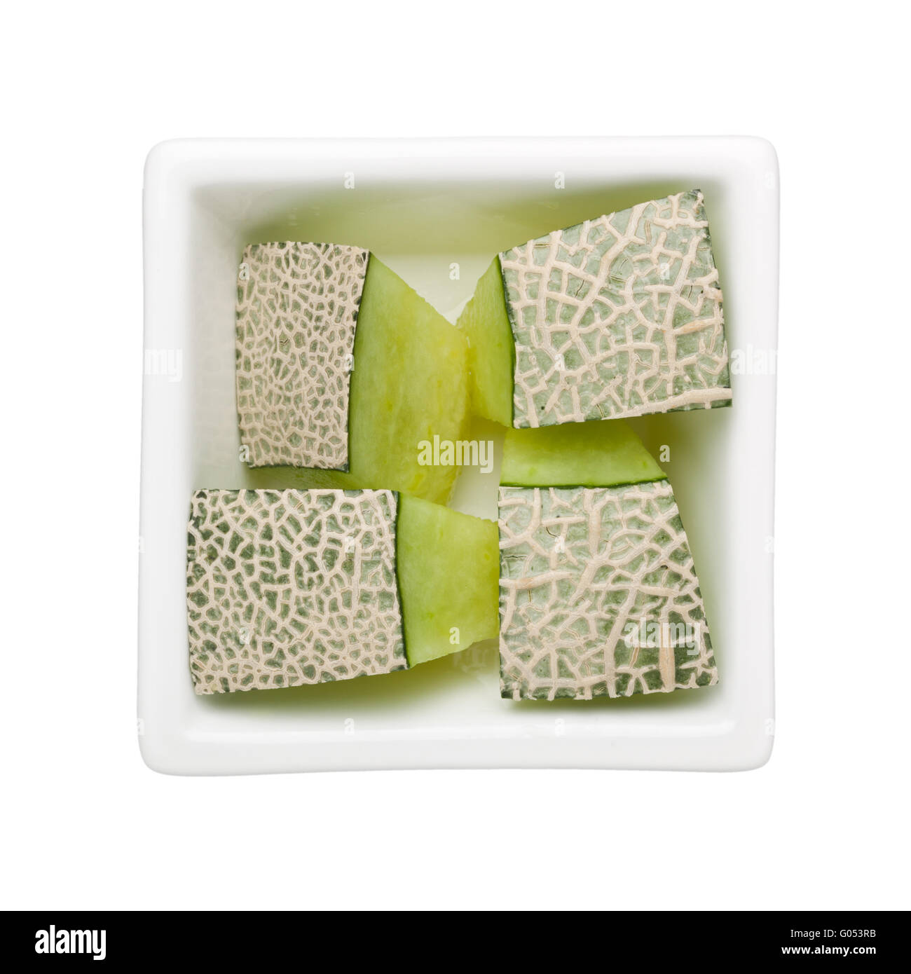 Pezzi di melone in un recipiente quadrato isolato su sfondo bianco Foto Stock