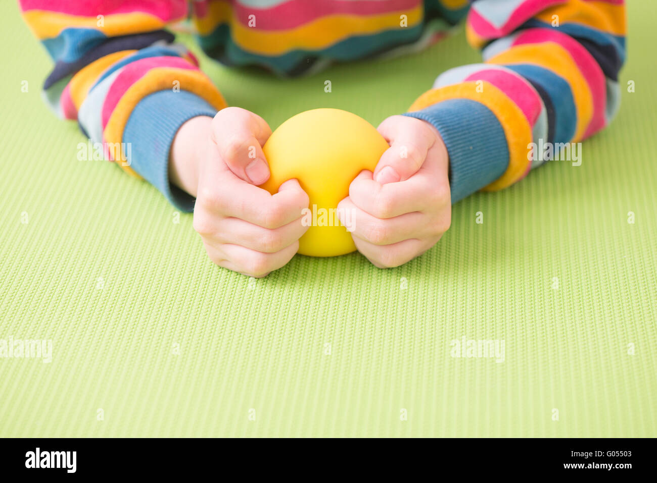 Bambino holding e la strizzatura giallo palla con le mani. Concetto di infanzia ansia e frustrazione e rabbia. Anche un simbolo di Foto Stock