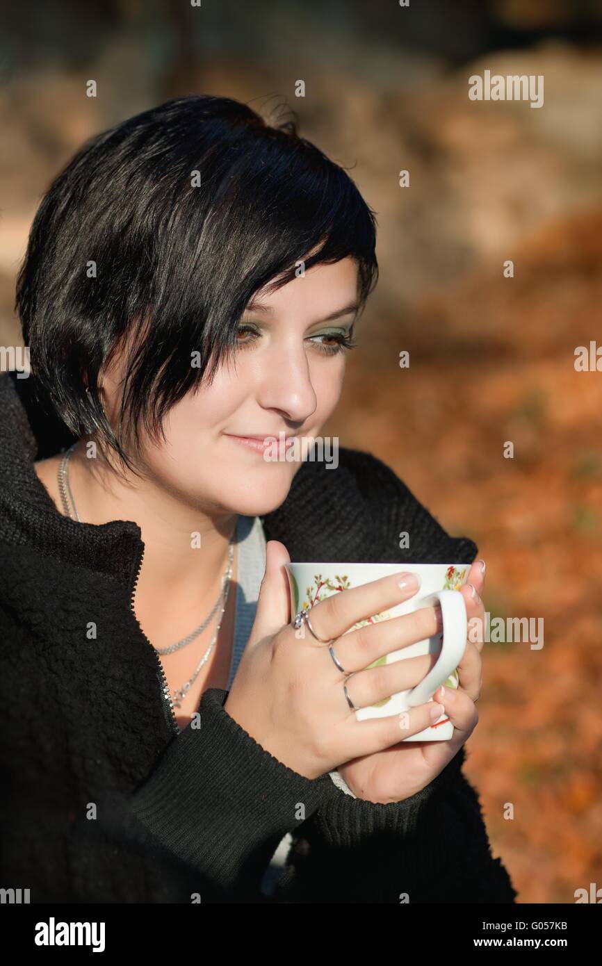 Donna attraente di bere il caffè nella foresta di autunno Foto Stock