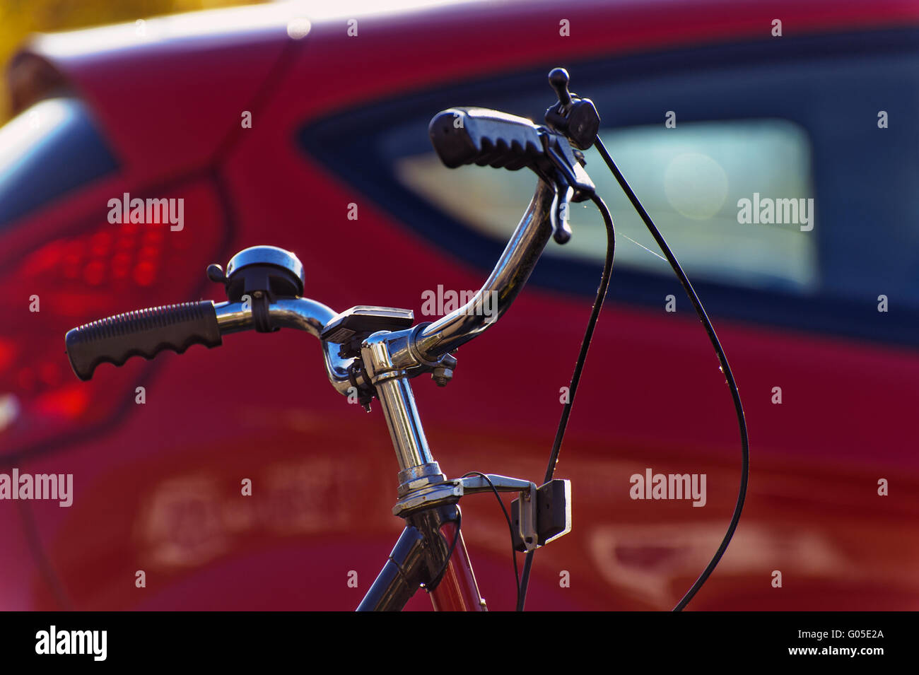 Manubrio di una bicicletta nella parte anteriore di un auto rossa Foto Stock
