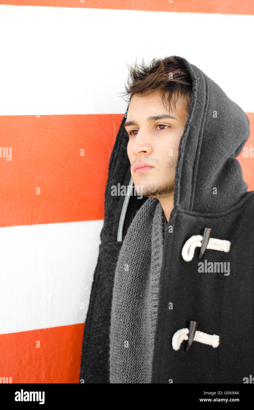 Attraente giovane hoodie contro il bianco e la parete arancione Foto Stock