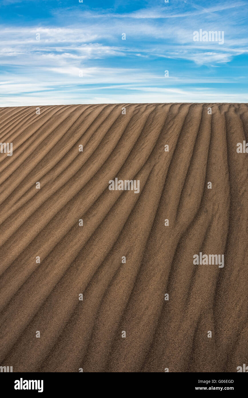 Textured dune di sabbia contro un cielo blu. Foto Stock